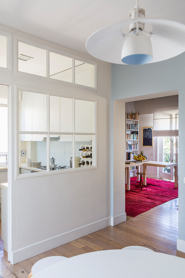 Kitchen separated from dining and living rooms by white wall with lattice windows