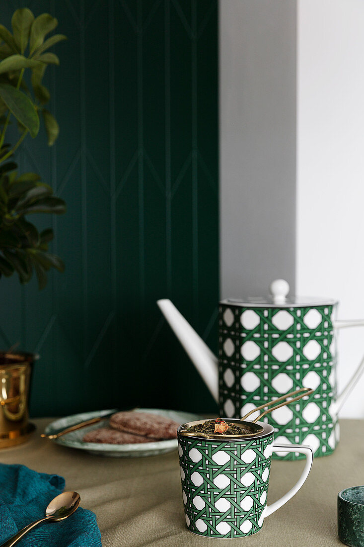 Mug and teapot with green woven pattern on table