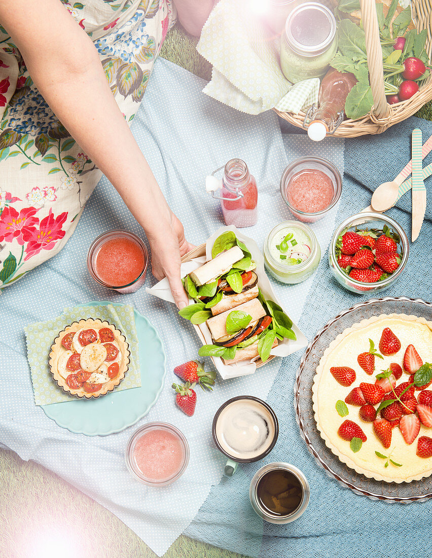 A picnic with strawberry cake, baguettes, quiches and smoothies