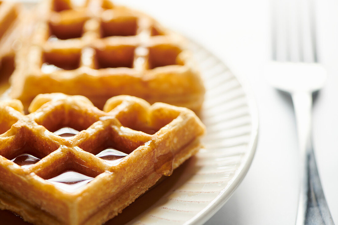 Belgian waffle pieces with syrup drpping down side