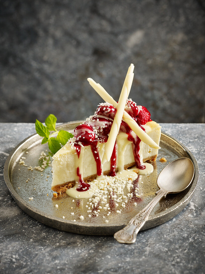 Ein Stück weißer Schokoladen-Käsekuchen mit Himbeeren