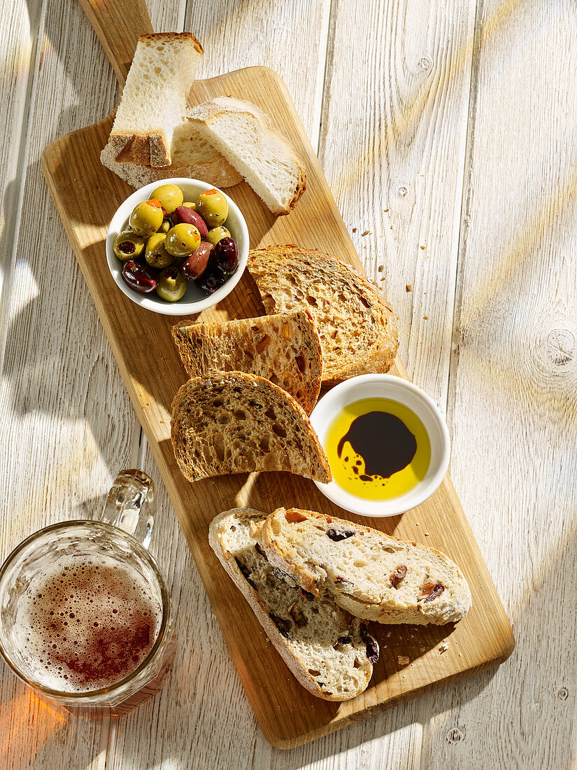 Brot, Oliven und Olivenöl auf Holzschneidebrett