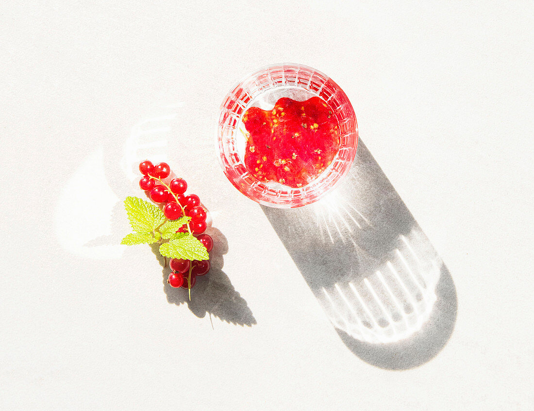 Summery currant cocktail in a glass casting a shadow