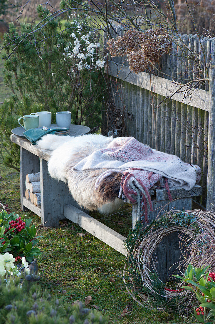 Bench with fur and blanket as a seat on the garden fence