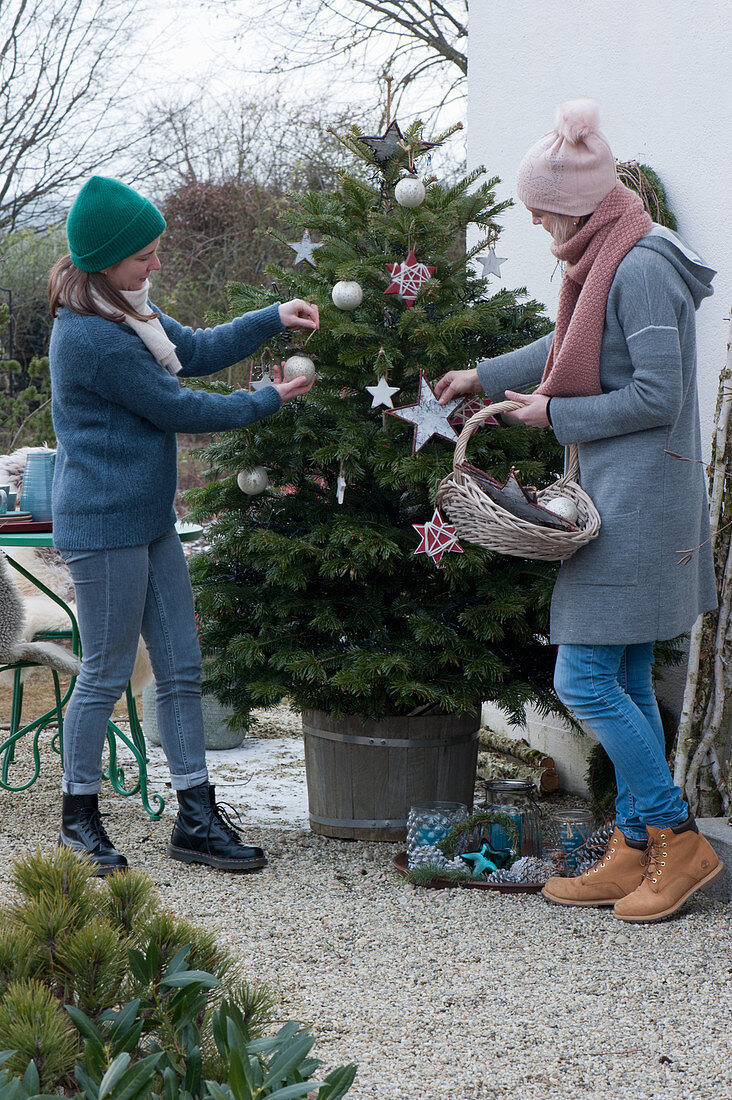 Women decorate Nordmann fir with stars and balls