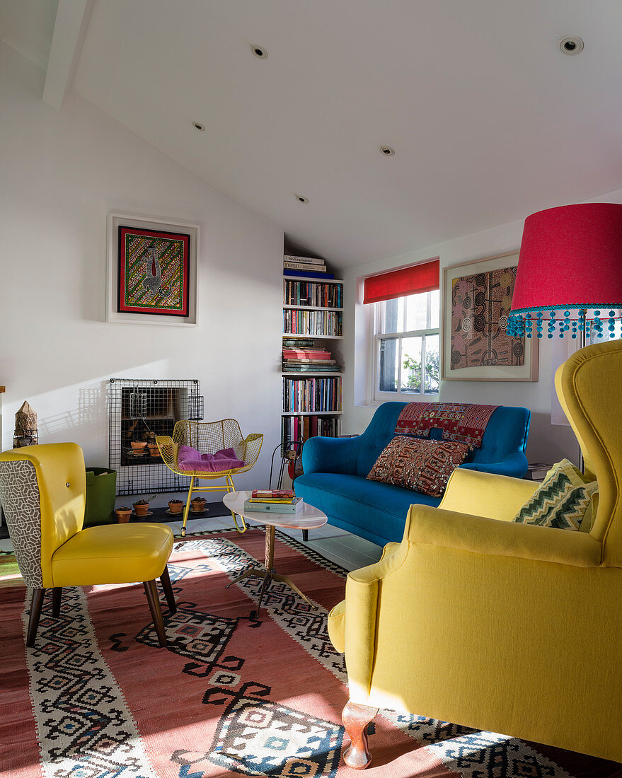 Upholstered seating in yellow and blue in small living room with colourful accessories