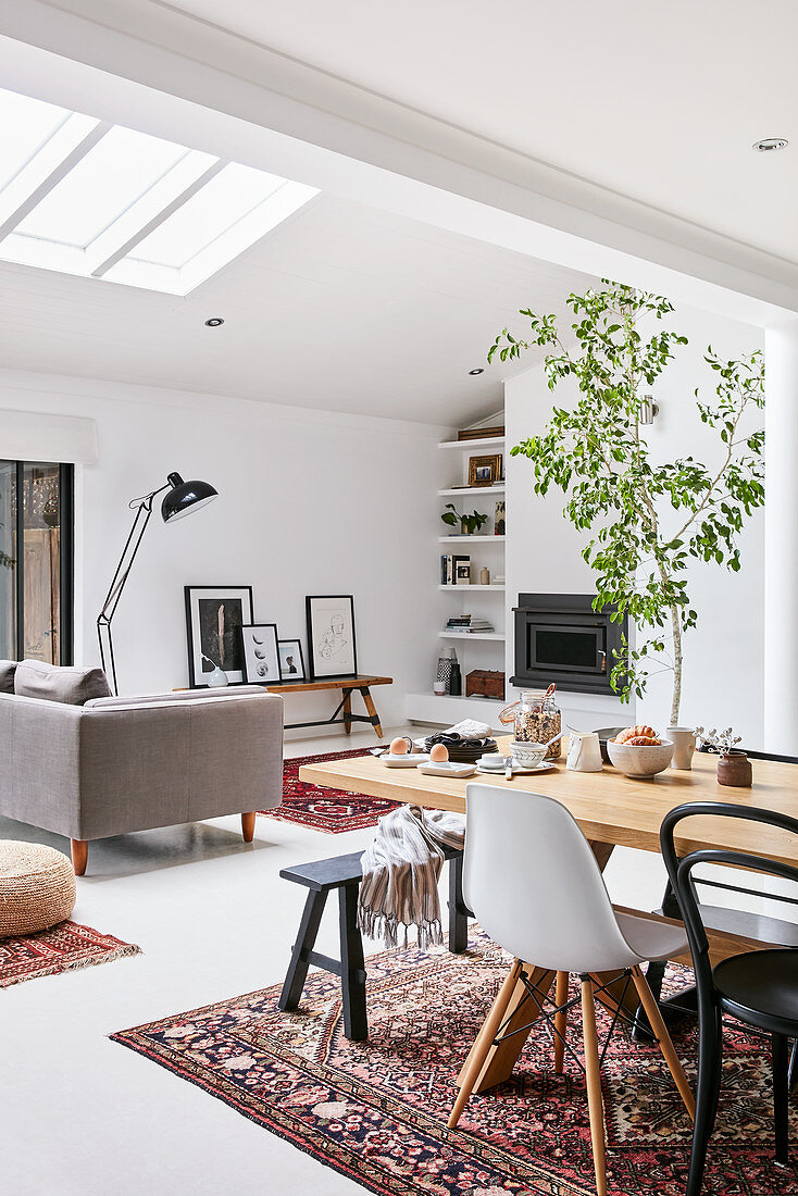 Wooden table with various chairs; couch under skylight in background