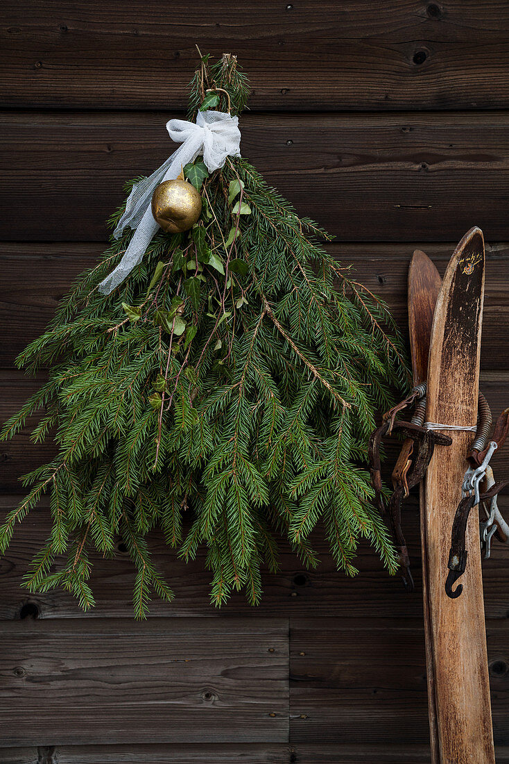 Weihnachtsdekoration aus Fichtenzweigen an rustikaler Holzwand