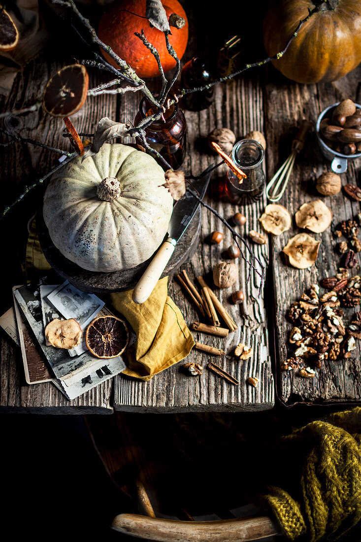 Herbststilleben mit Kürbissen, Gewürzen, Nüssen und Trockenfrüchten auf Holztisch