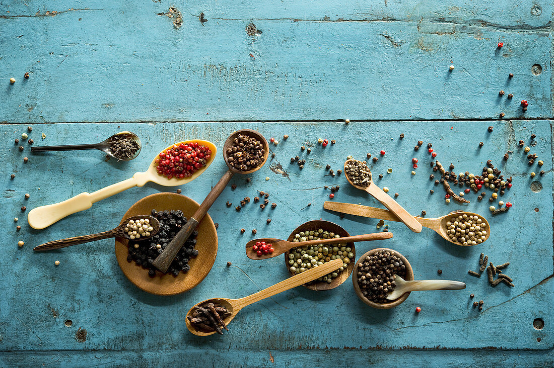 An arrangement of various types of peppers in bowls and on spoons