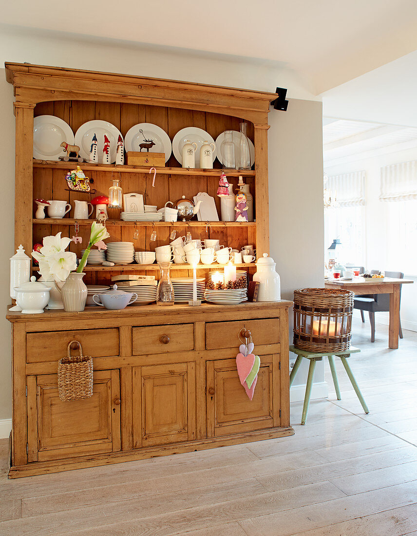 White crockery, candles and winter decorations on rustic kitchen dresser