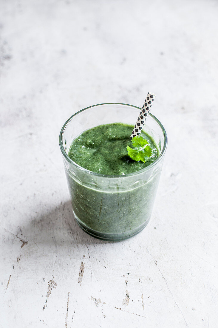 Green smoothie made with mango, banana, orange juice, cilantro, ginger, kiwi and chlorella