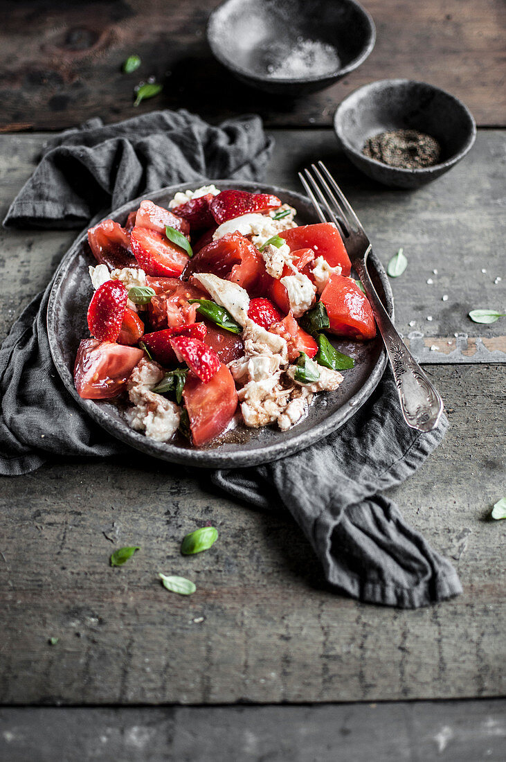 Rustic caprese salad made with tomatoes, mozzarella cheese, strawberries, fresh basil, olive oil and balsamic vinegar