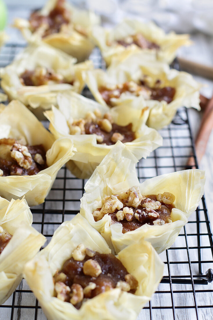 Mini apple pies with phyllo crust cooling on a bakers rack
