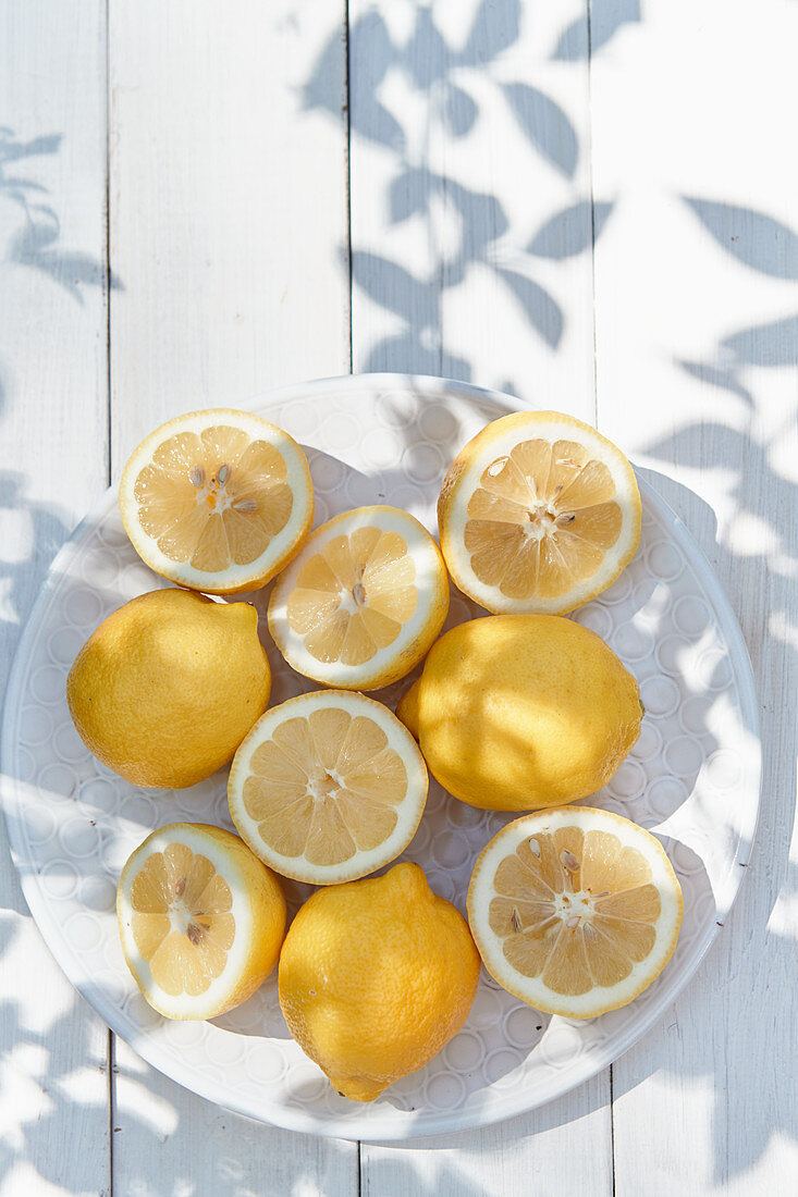 Zitronen, ganz und halbiert, auf Teller