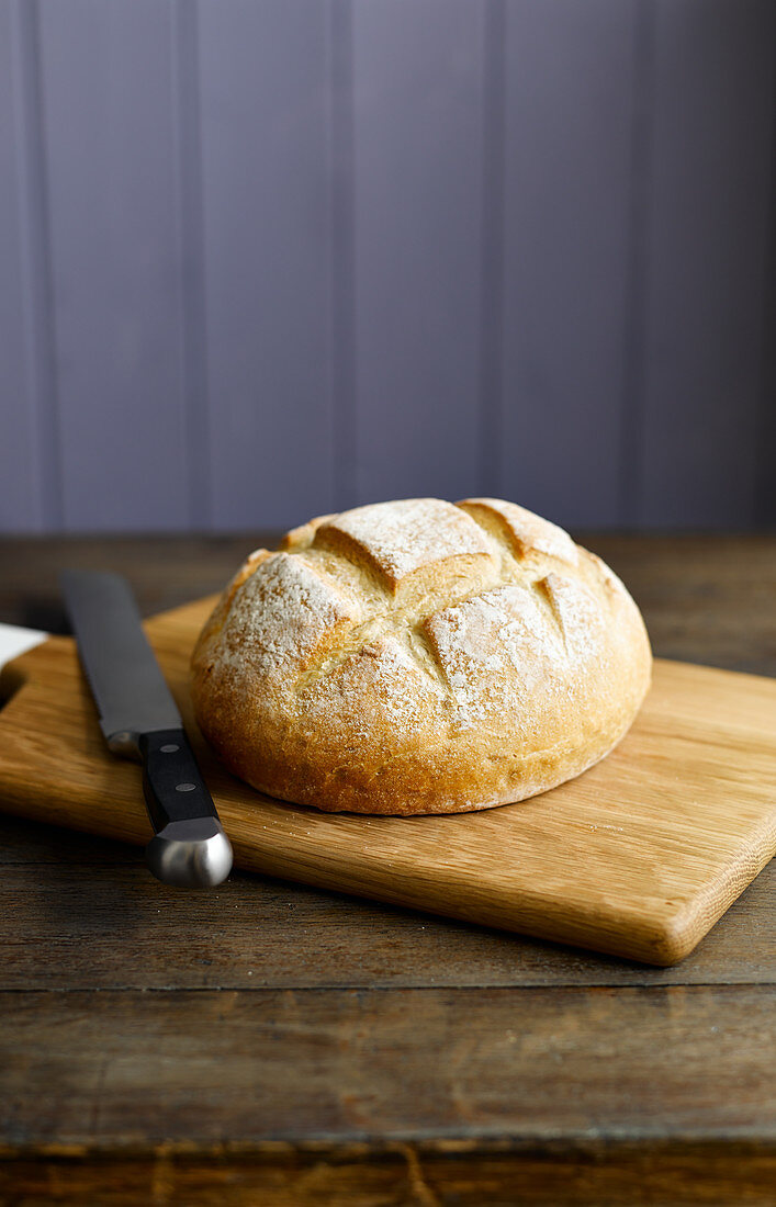 Rundes Weißbrot auf Schneidebrett mit Messer