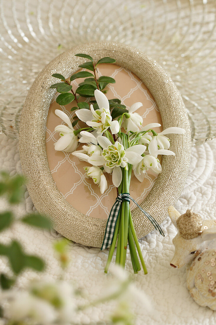 Posy of snowdrops lying on picture frame