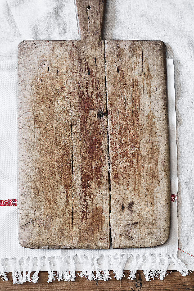 An old wooden chopping board on a tea towel
