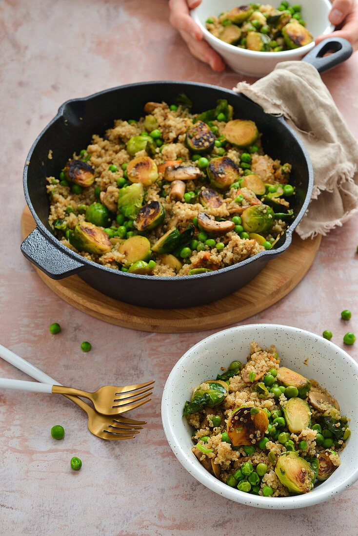 Quinoa with caramelized Brussels sprouts green peas and sweet potatoes dish in a pan A healthy vegetarian dish