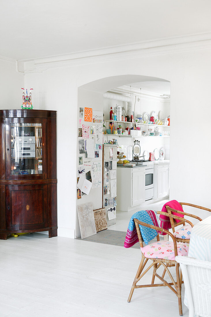 Dining table and antique corner cupboard next to open doorway leading into kitchen