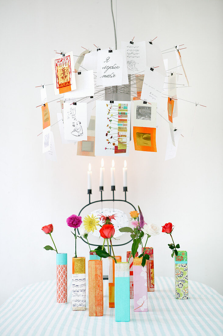 Postcards clipped to Zettel'z lamp over colourful vases holding single flowers