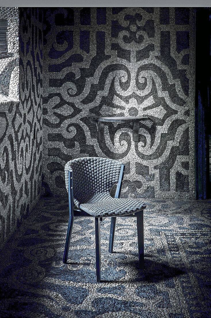 Black Mahogany chair with woven seat and back in interior with mosaic-tiled walls and floor