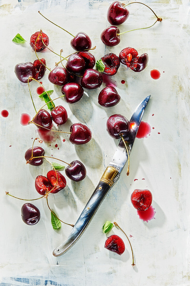 Cherries, some sliced, with a knife