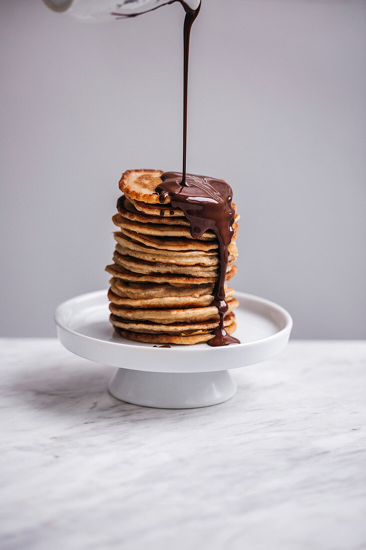 Schokolade fließt auf einen Stapel Pancakes