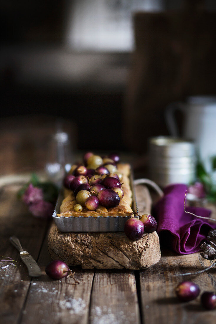 Tart with red and green grapes on wooden table