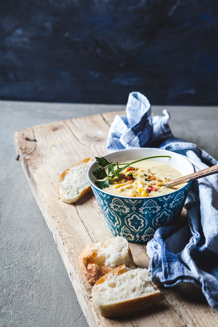 Corn chowder with bread on a rustic wooden board