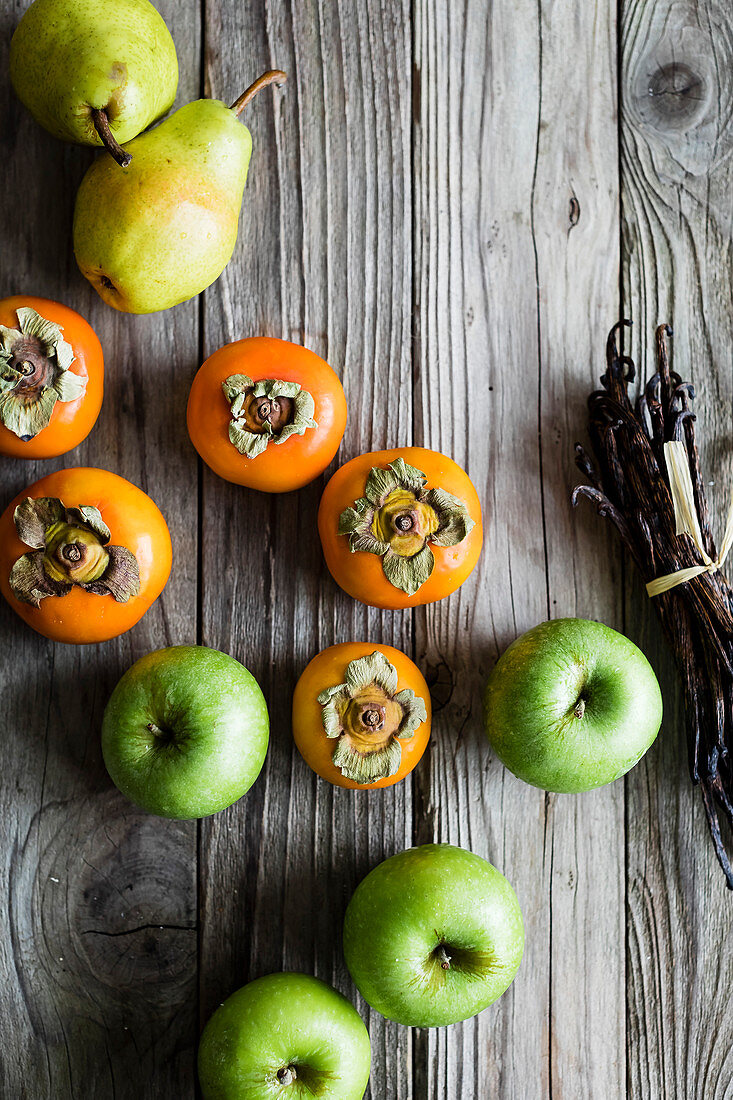 Persimmon and apples on a wooden background