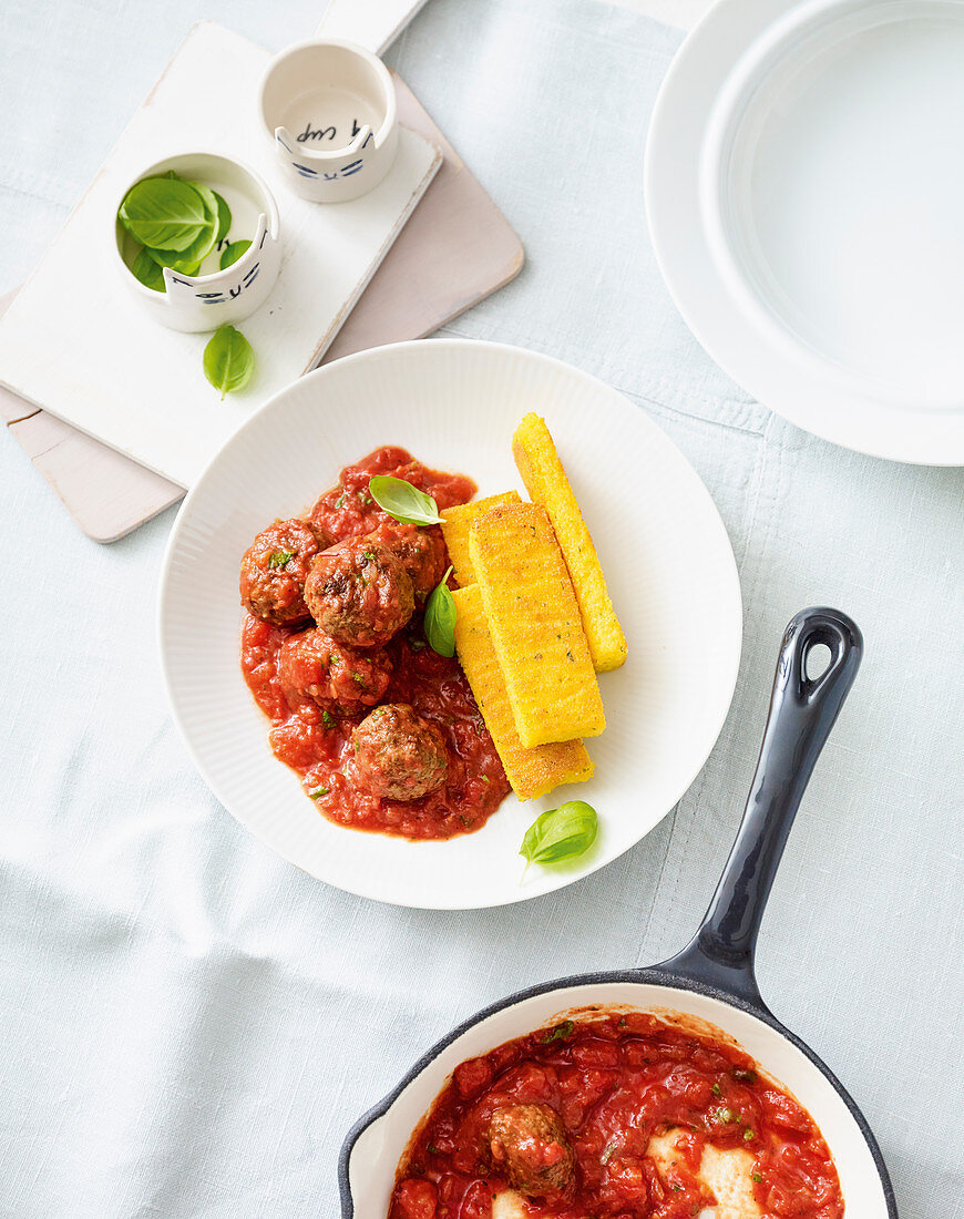 Polenta slices with meatballs in tomato sauce