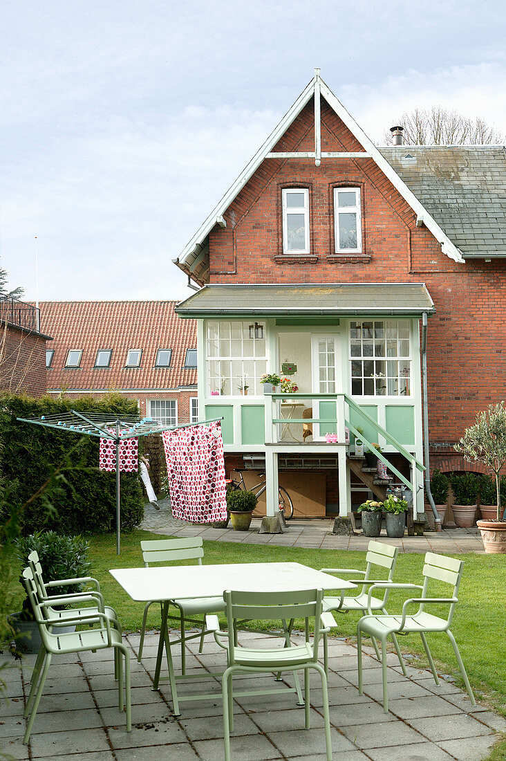 Green garden furniture on terrace in garden of brick house