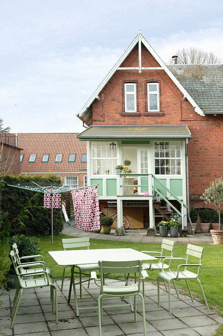 Grüne Gartenmöbel auf der Terrasse im Garten vorm Backsteinhaus