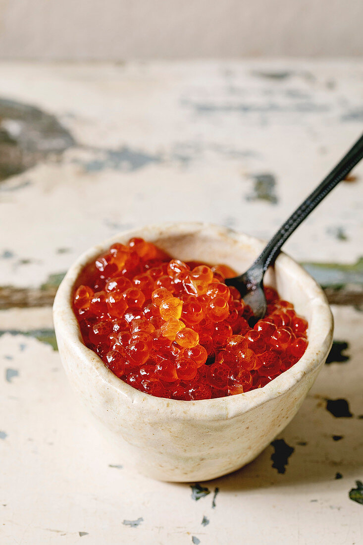 Roter Lachskaviar mit Löffel in Keramikschälchen