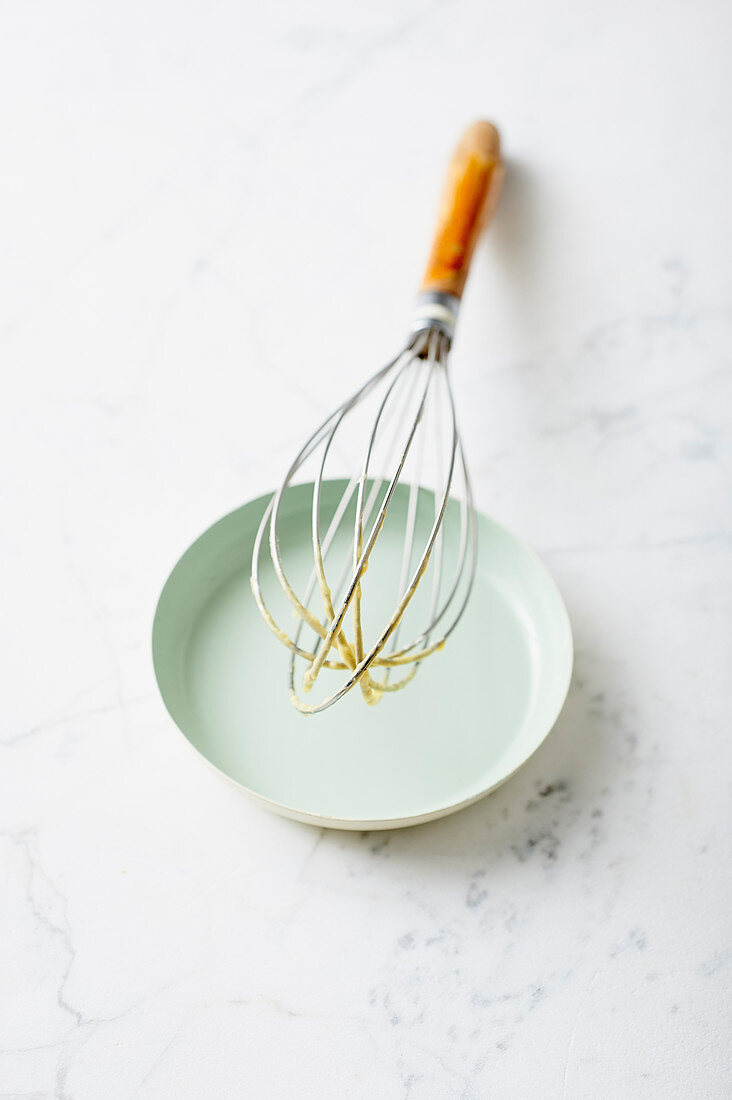 Cake mix on a whisk leaning on a plate