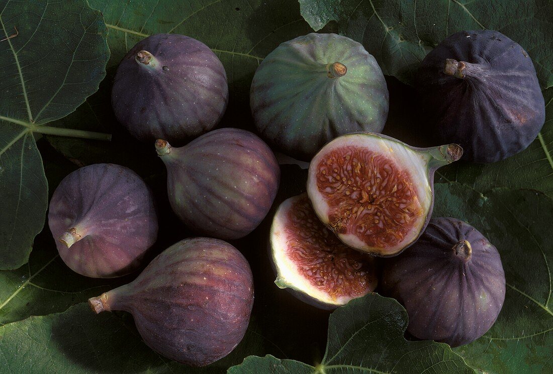 Several figs with fig leaves, one halved