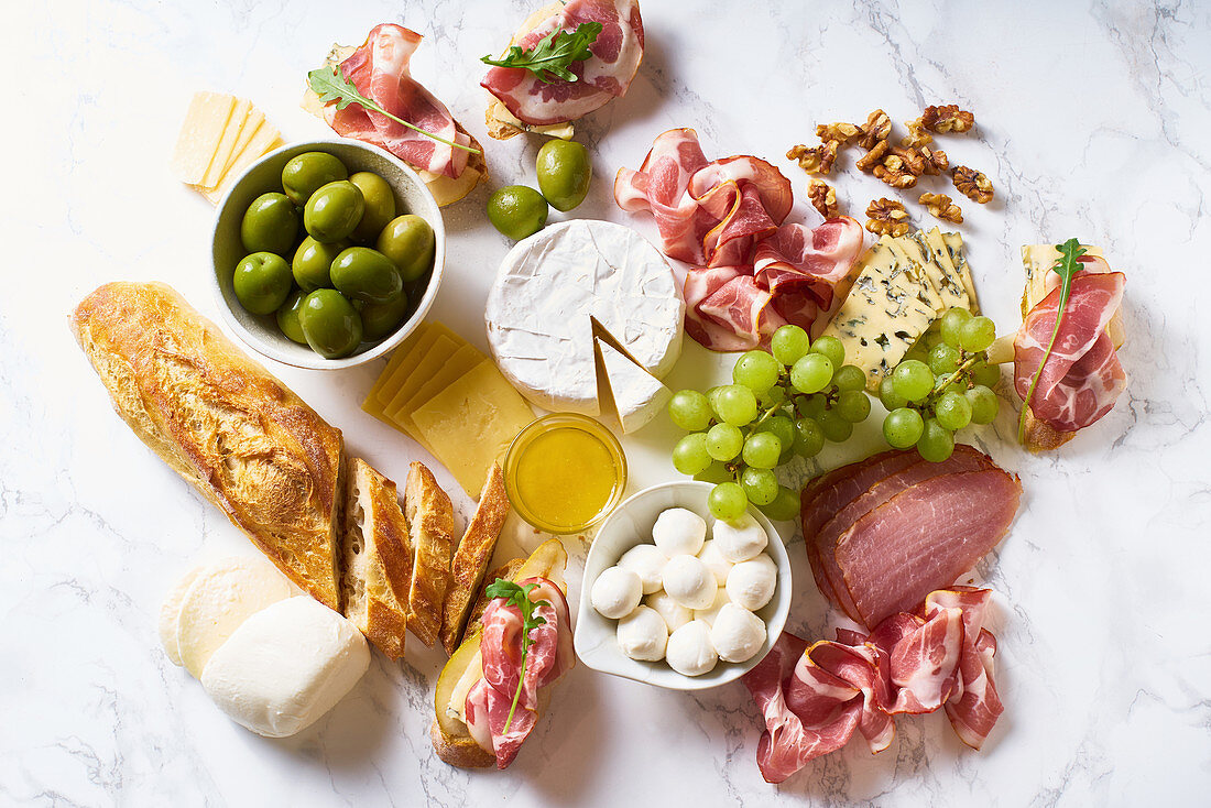 Käse-Schinken-Platte mit Walnüssen, Oliven, Trauben, Brot und Crostini