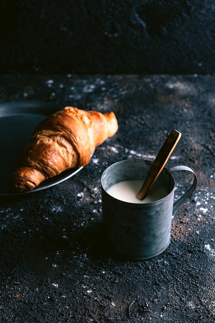 Croissant and milk on table