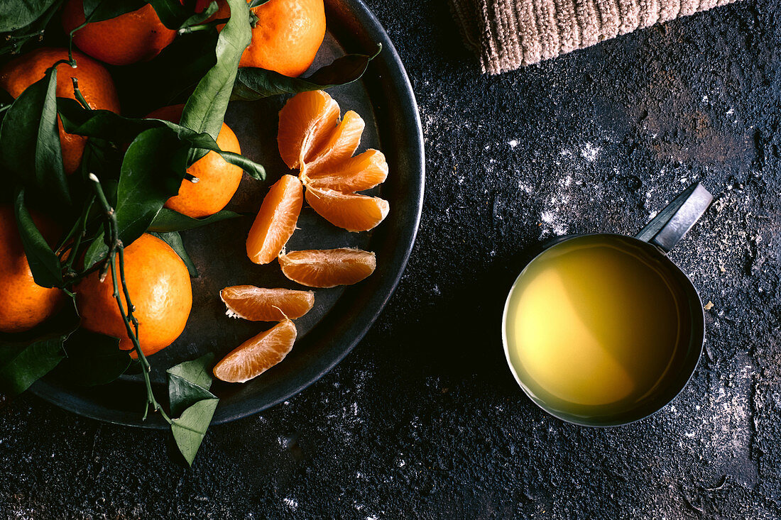 Mug with fresh fruit juice and plate with ripe tangerines