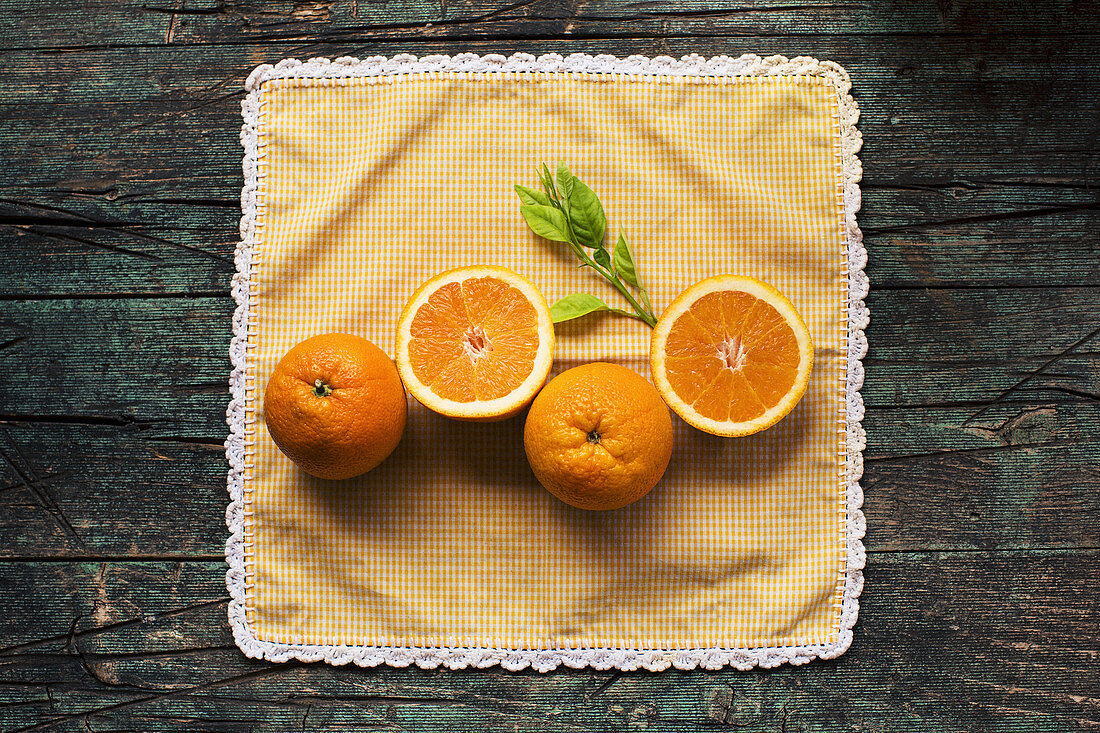 Orangen und Orangenhälften auf Serviette mit Spitzenbordüre