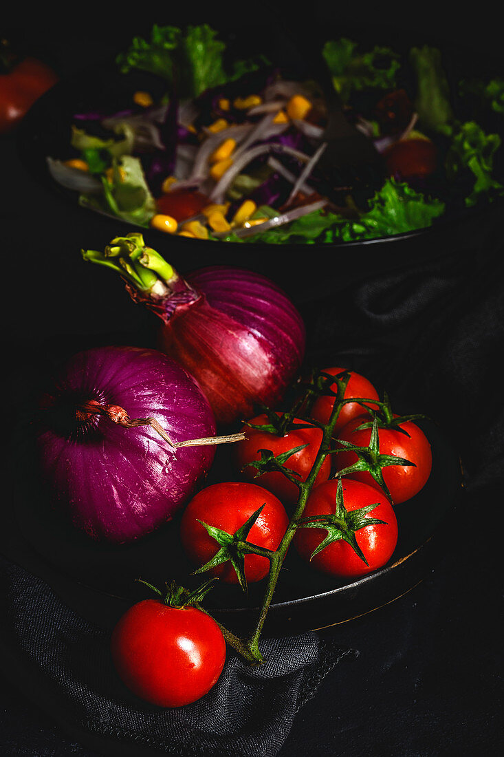 Healthy vegan food with fresh lettuce, cherries tomatoes, red onion and corn on dark background