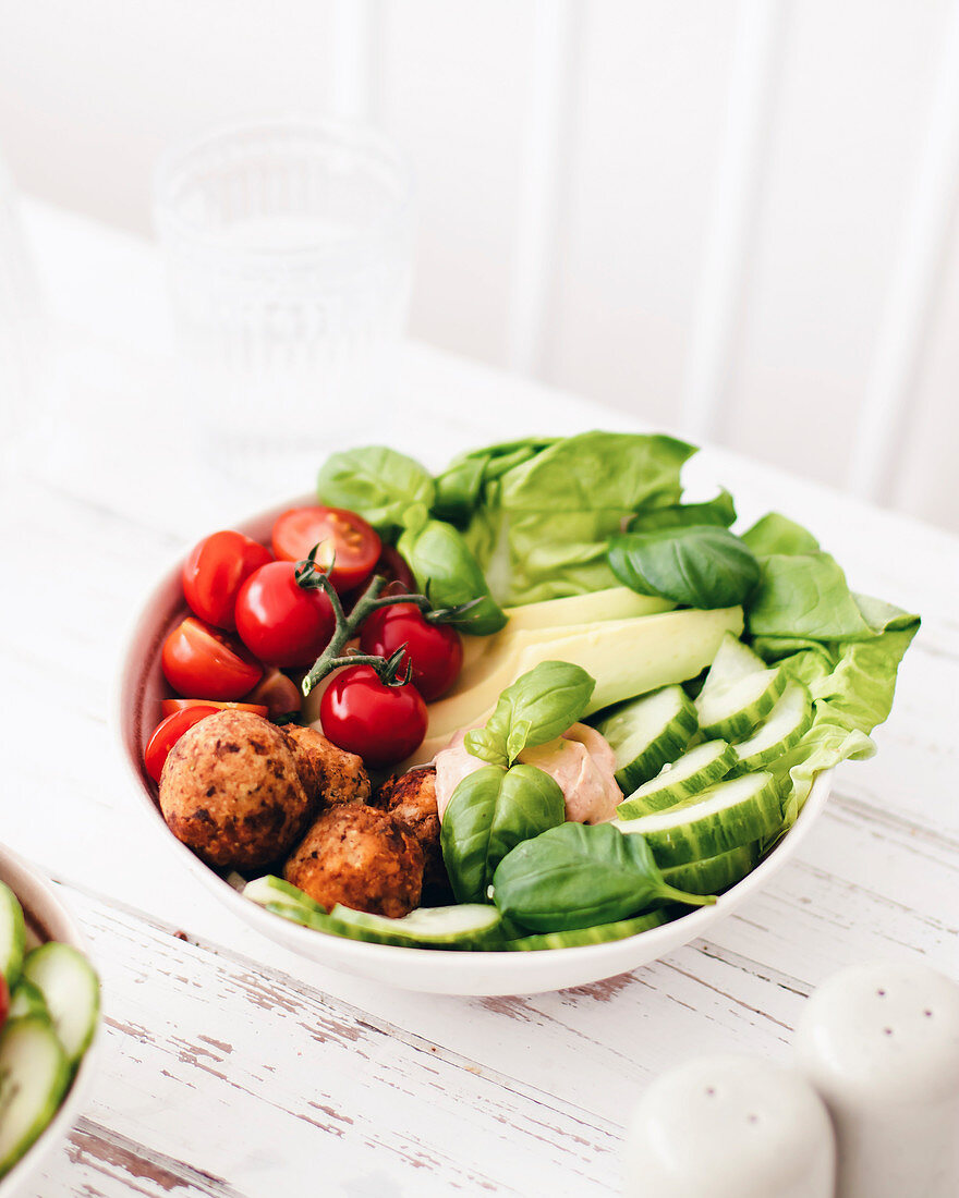 A salad bowl with falafel, cucumber, avocado and tomatoes