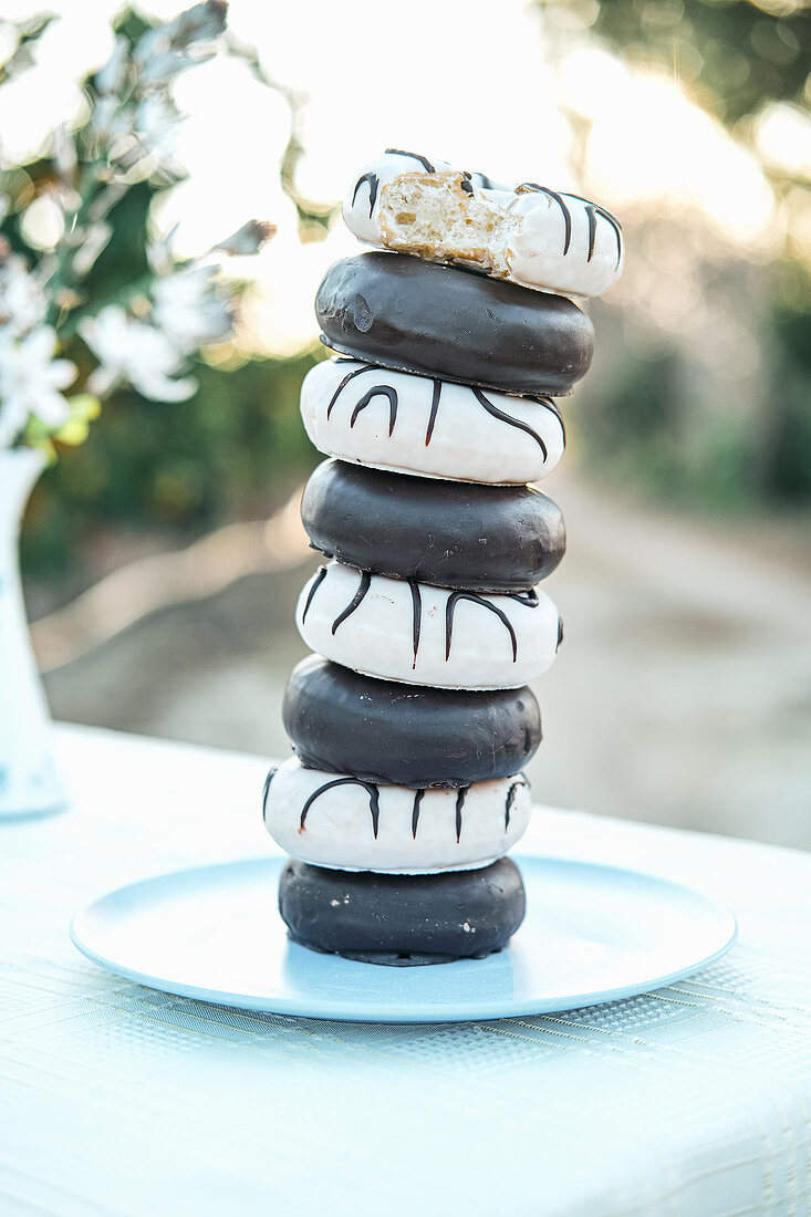 Yummy donuts with icing and chocolate ganache stacked on plate