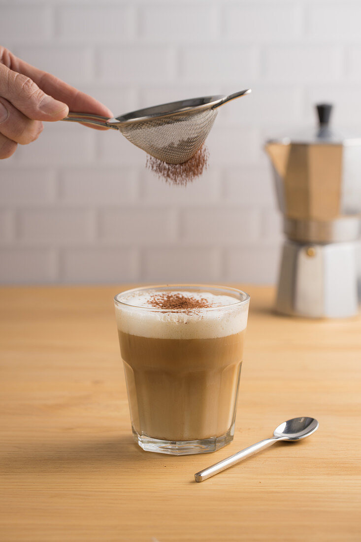 Cappuccino im Glas mit Kakao bestauben