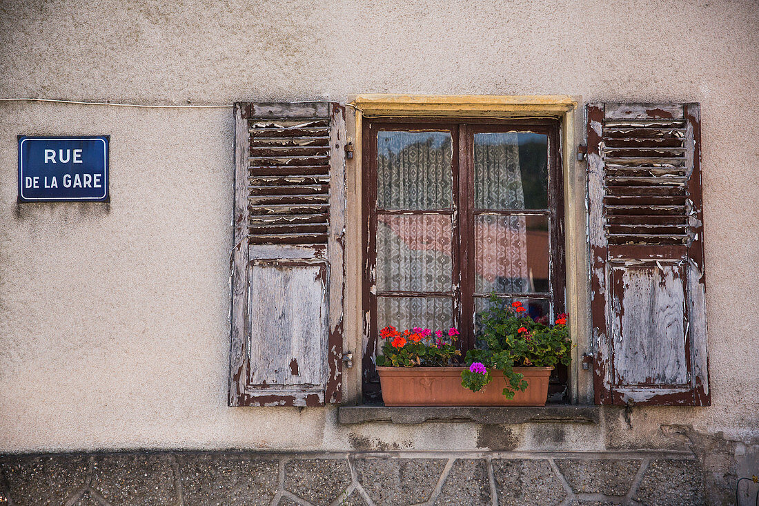 Geranien im Fenster mit geöffneten Fensterläden und Straßenschild, Gemeinde Apach, Frankreich (Dreiländereck)