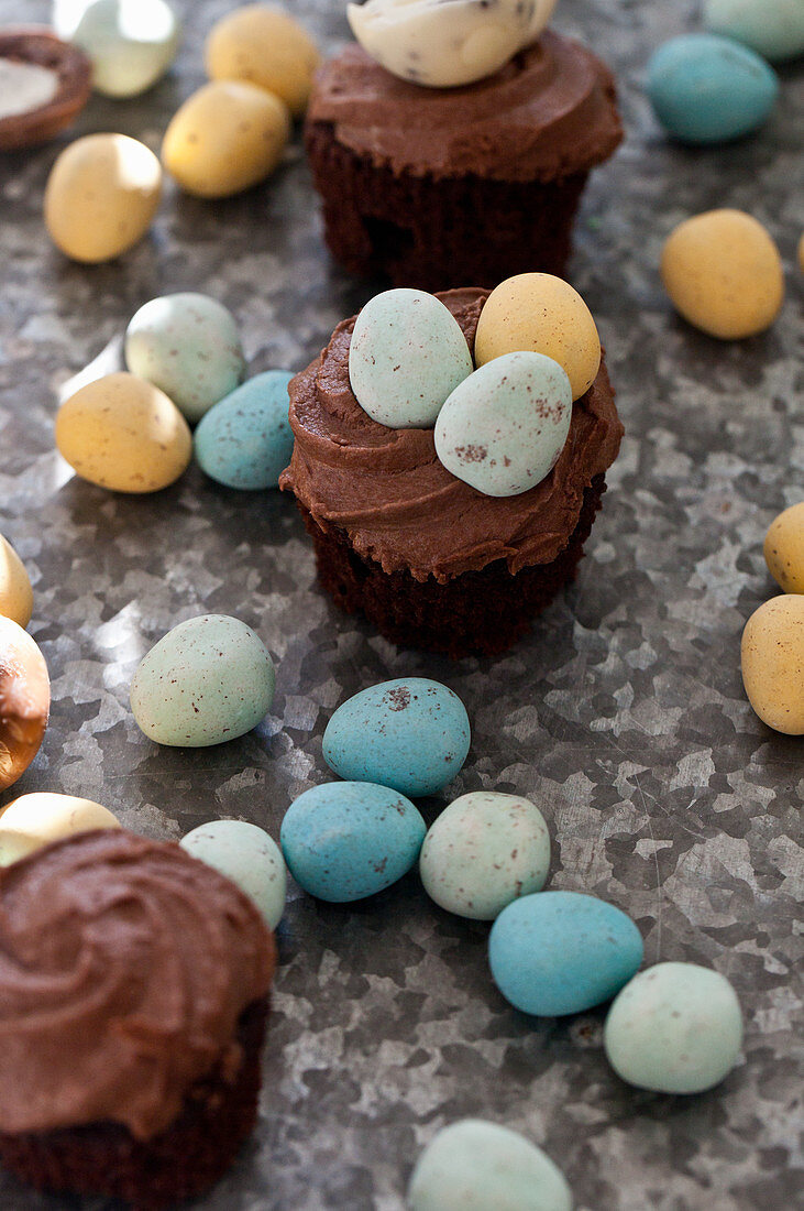 Chocolate cupcakes with mini chocolate eggs on a textured surface