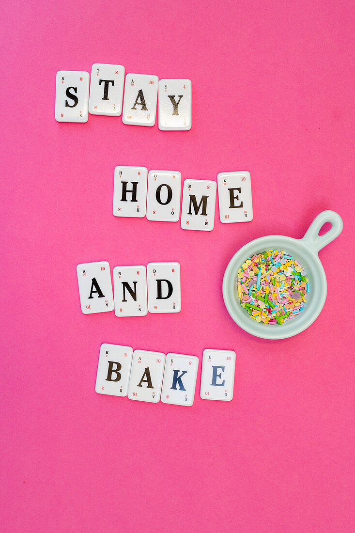 Schriftzug Stay Home And Bake und bunte Zuckerstreusel