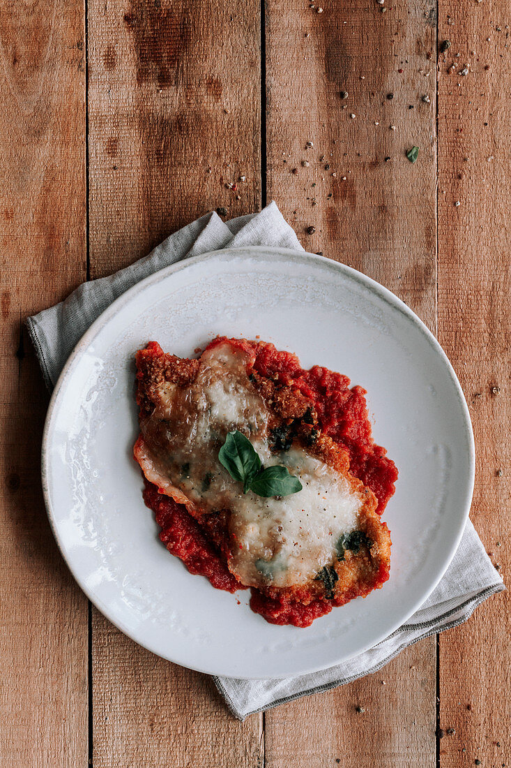 Gebratene und gratinierte Hähnchenbrust auf Tomatensauce mit Mozzarella und Parmesan