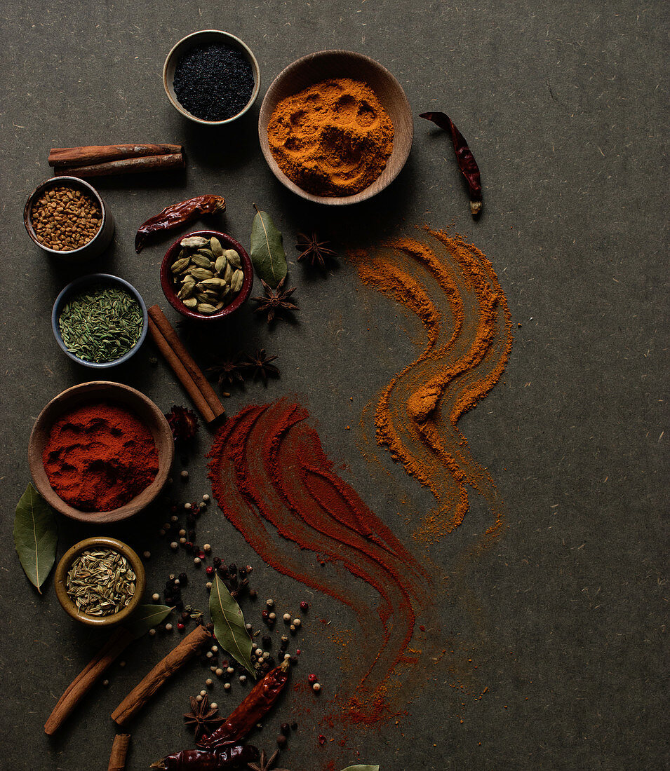 Different kinds of natural aromatic spices placed on dark gray background
